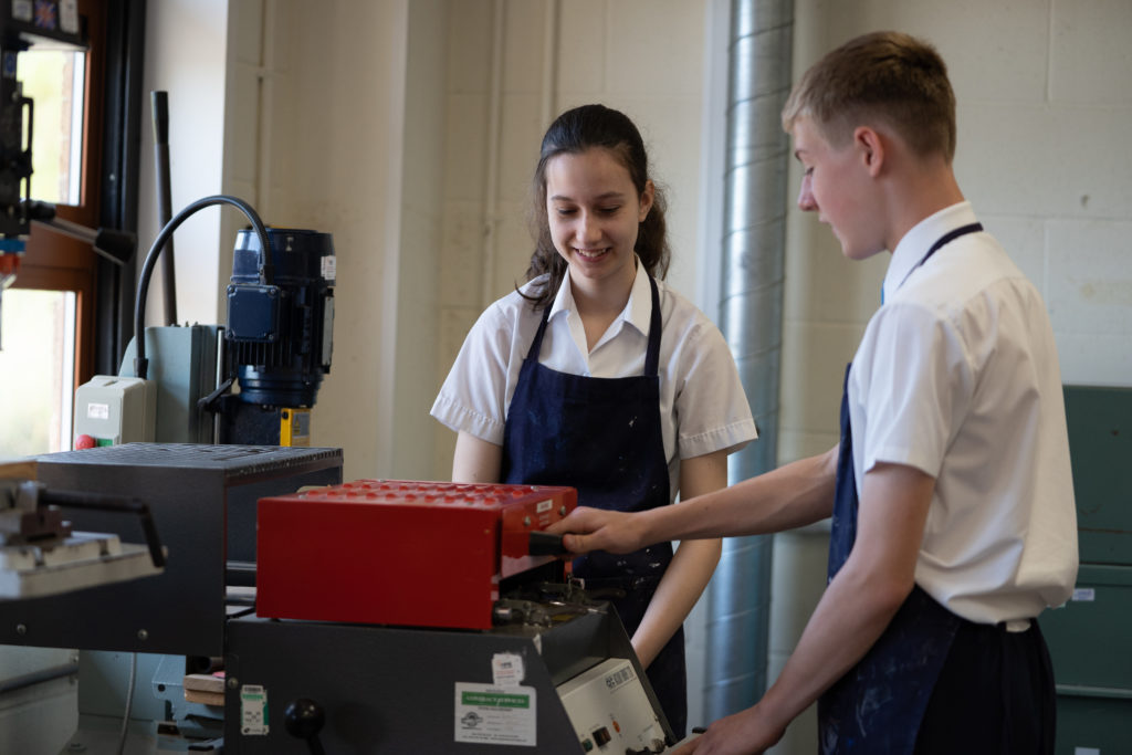 A girl and a boy are pictured operating a piece of machinery during a Design & Technology class.