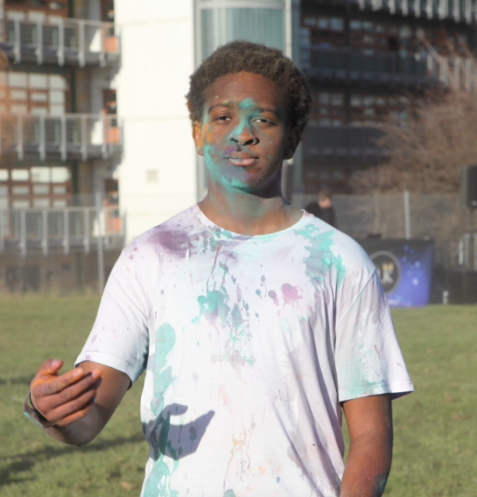 A male student is pictured posing for the camera, covered in multi-coloured powder after celebrating the Hindu festival of Holi on the academy grounds.