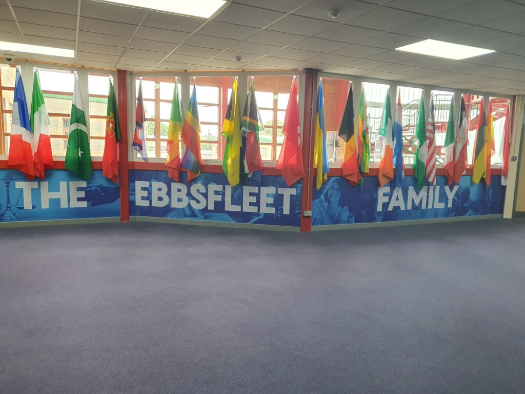 Photo of a corridor in the Ebbsfleet Academy building, featuring a wall decorated with the flags of different countries around the world.