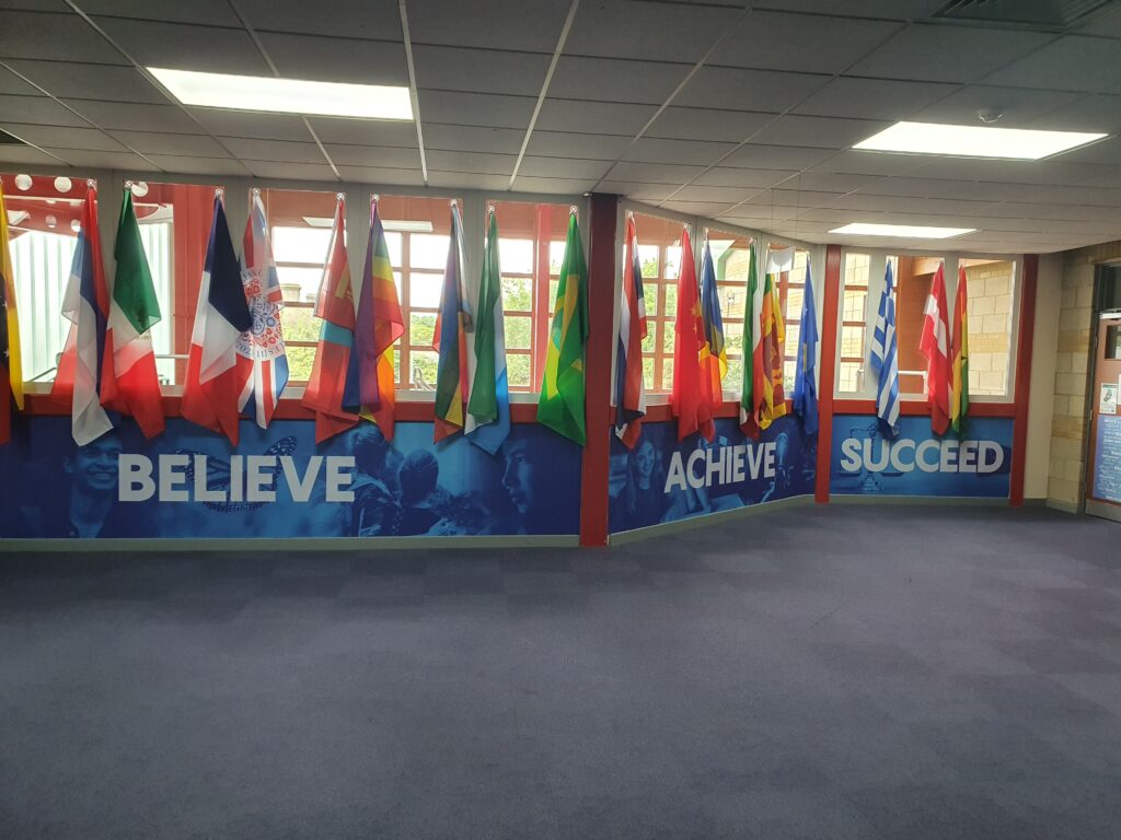 Photo of a corridor in the Ebbsfleet Academy building, featuring a wall decorated with the flags of different countries around the world.
