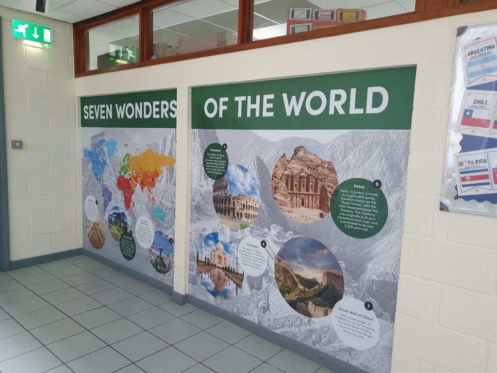 Photo showing a corridor inside the Ebbsfleet Academy building, featuring information and images of the Seven Wonders of the World.
