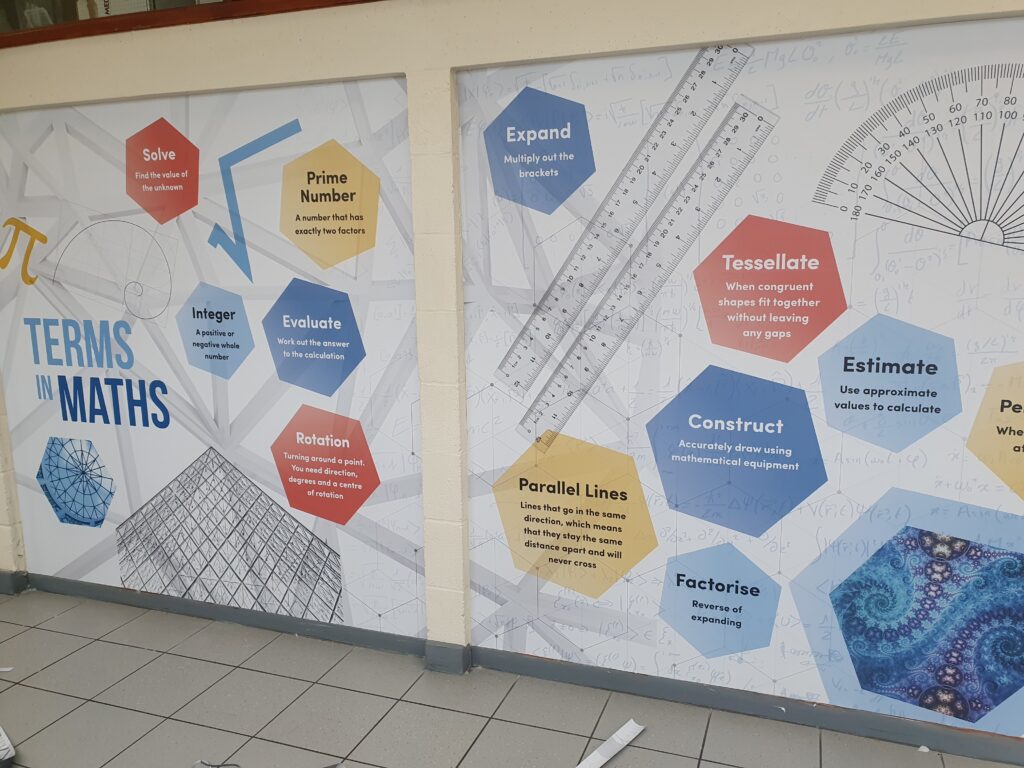 Photo showing a corridor inside the Ebbsfleet Academy building, featuring information and images of different topics in Mathematics.