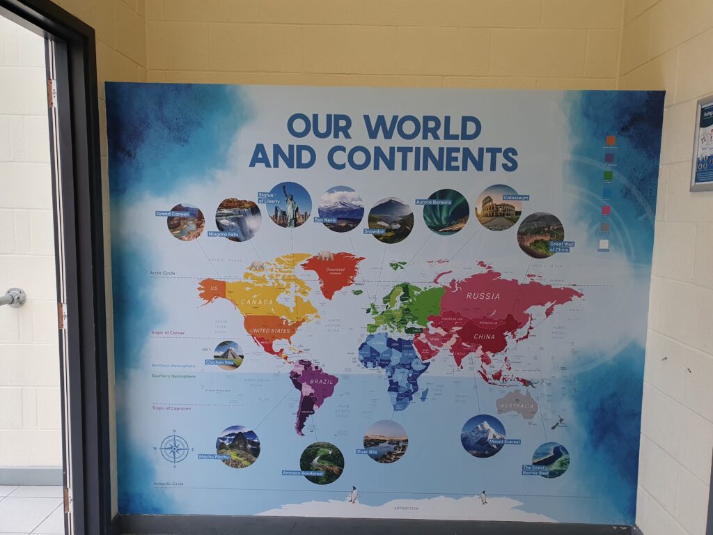 Photo showing a corridor inside the Ebbsfleet Academy building, featuring information and images of different continents around the world.