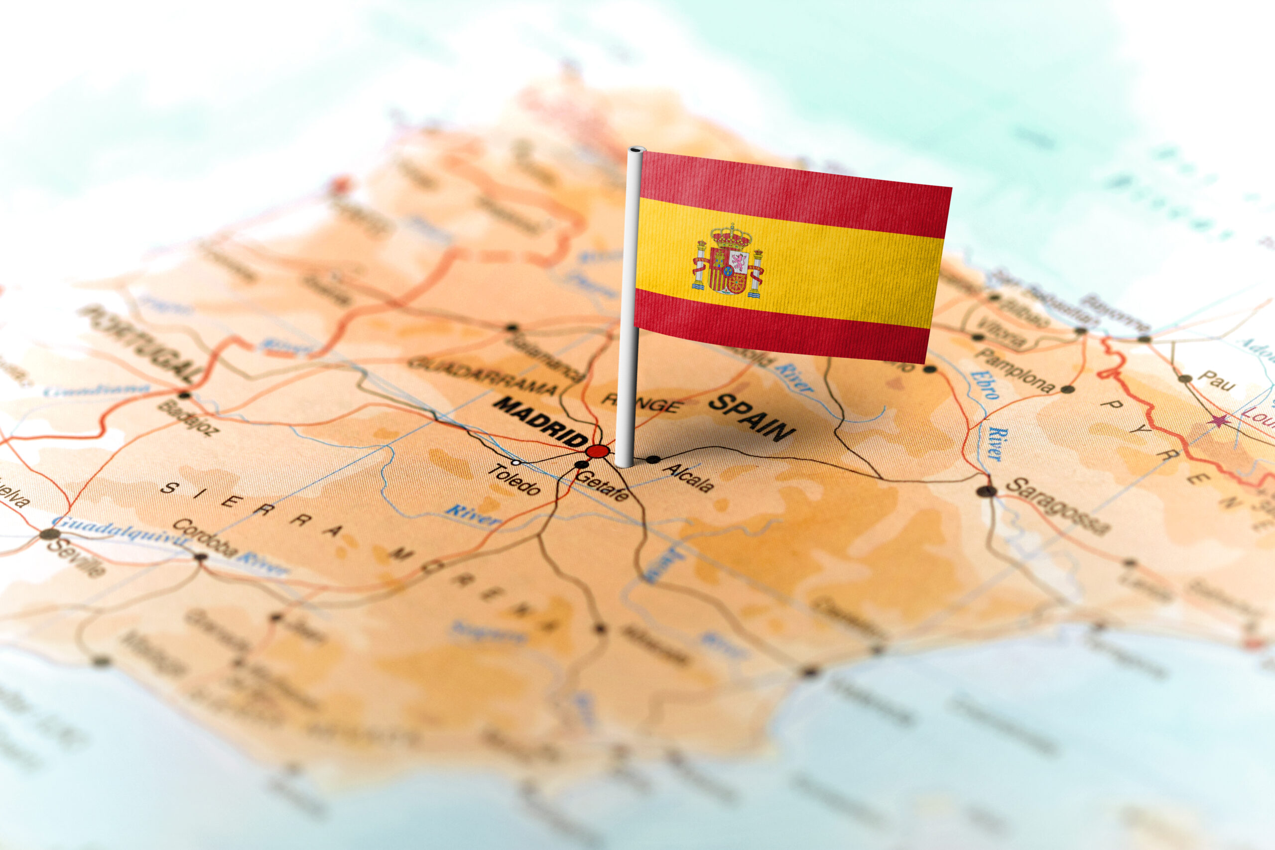 A photo showing a map of zoomed in on the country of Spain with a Spanish flag pinned onto the capital city, Madrid.