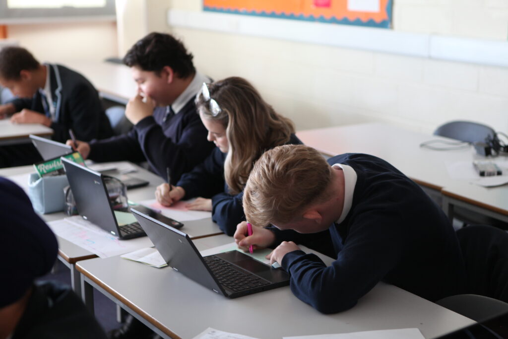A small group of Year 11 students are seen concentrating on their work, whilst sat at their desks during a Macbeth Workshop.