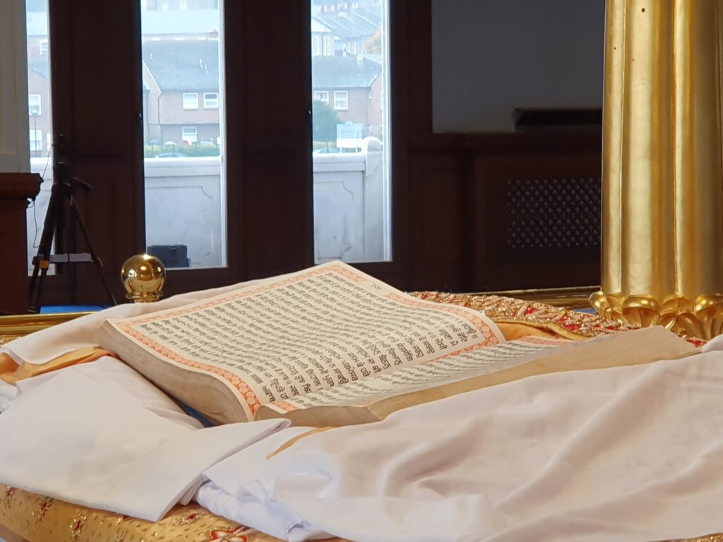 A Sikh religious text seen laid out on white sheets inside a Gurdwara temple.